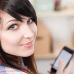 Młoda ładna brunetka kobieta w słuchawkach trzymając telefon komórkowy