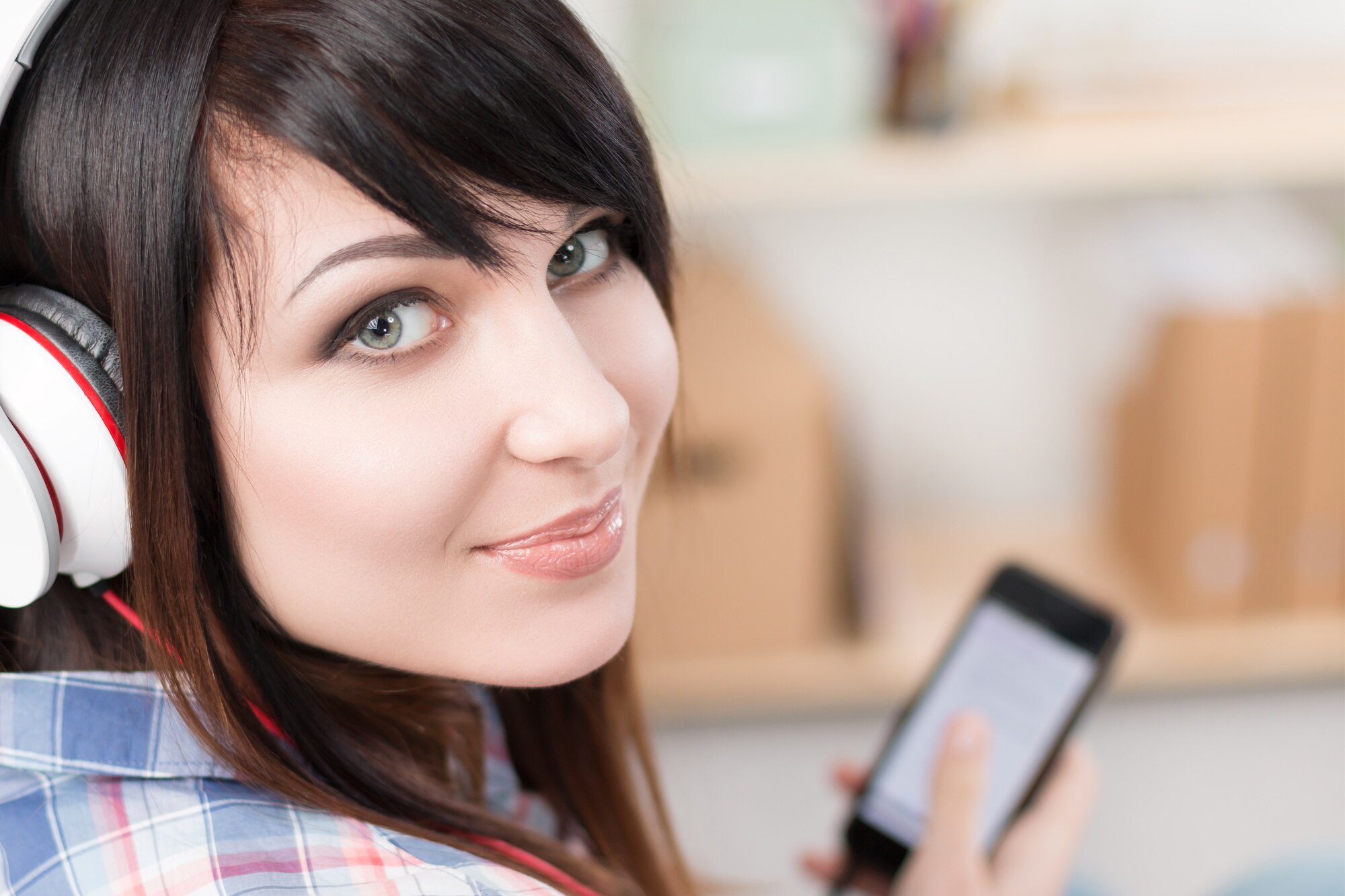 Młoda ładna brunetka kobieta w słuchawkach trzymając telefon komórkowy