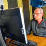 Mężczyzna w średnim wieku z okularami siedzący przy biurku dojrzały mężczyzna używający komputera osobistego koncepcja starsza