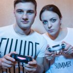 Portret młodej i atrakcyjnej pary chłopca i dziewczyny grających w gry wideo siedzących na kanapie przed telewizorem w domu w miłej atmosferze