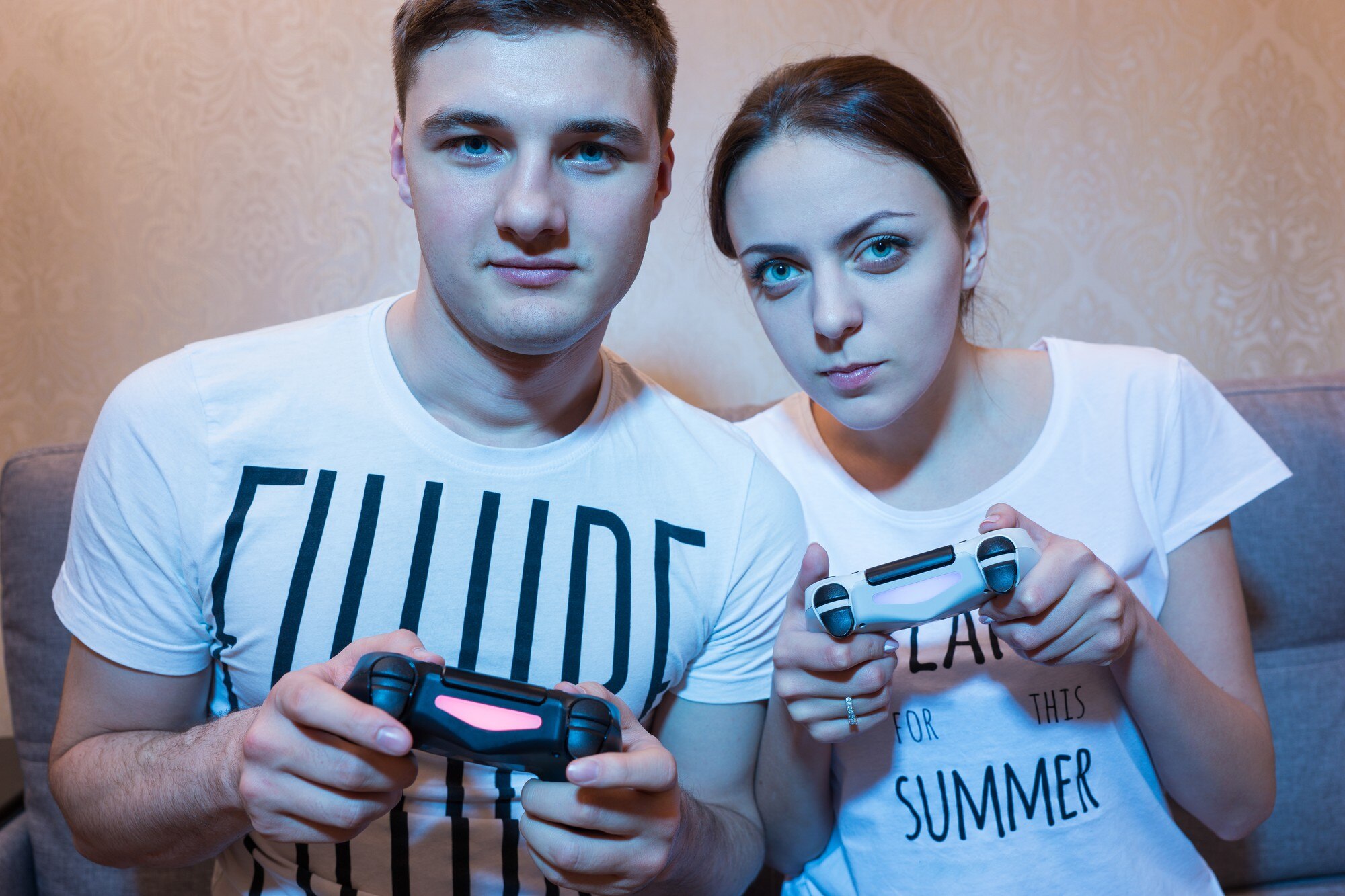 Portret młodej i atrakcyjnej pary chłopca i dziewczyny grających w gry wideo siedzących na kanapie przed telewizorem w domu w miłej atmosferze