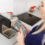 dziewczyna siedzi na kanapie i trzyma telefon z programem smart home na ekranie