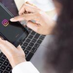 Bangkok/Tajlandia – 06 sierpnia 2021: Przedsiębiorcy siedzący w biurze, pracujący z komputerem, posiadający systemy operacyjne smartfona z logo aplikacji społecznościowych Instagram.