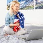 Młoda kobieta z flagą USA przy użyciu komputera przenośnego, dzień niepodległości online.