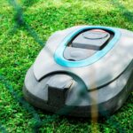 Automatyczna kosiarka do trawy letniej. Nowoczesny ogród w słoneczny dzień na wsi.