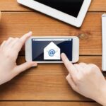 koncepcja technologii, biznesu, komunikacji, ludzi i reklamy - zbliżenie kobiety z wiadomością e-mail na ekranie smartfona i filiżanką kawy na drewnianym stole