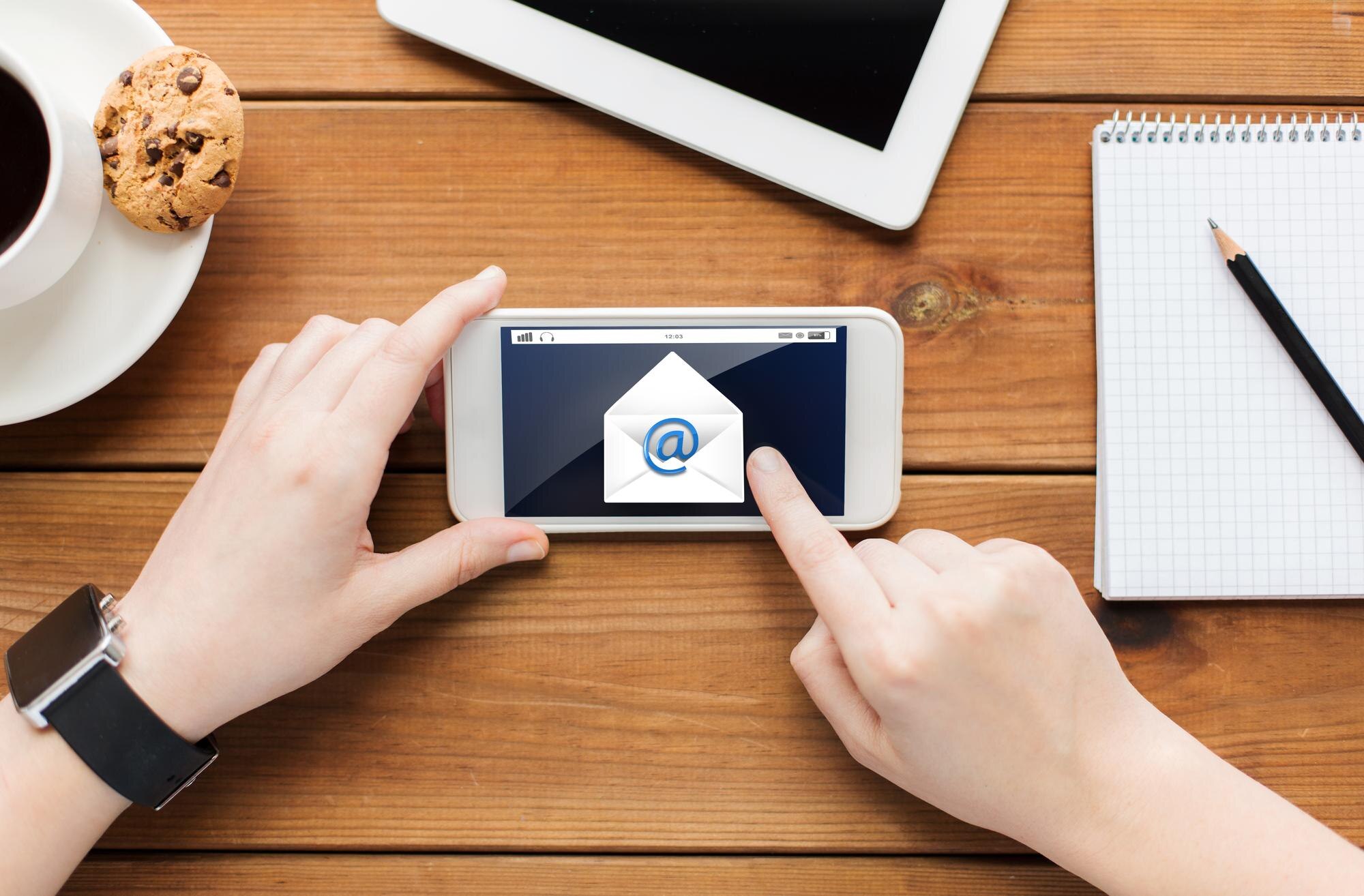 koncepcja technologii, biznesu, komunikacji, ludzi i reklamy - zbliżenie kobiety z wiadomością e-mail na ekranie smartfona i filiżanką kawy na drewnianym stole