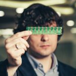 poważny człowiek zamknął oczy mikroukładem. RAM w rękach biznesmena. Anonimowy chowający się za chipem. Pamięć o dostępie losowym.