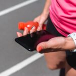 Sportsmenka patrzeje smartphone podczas gdy jogging na bieg śladzie